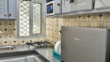 Een keuken met grijze kastjes, een roestvrijstalen fornuis en een koelkast.