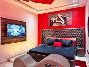 Een moderne slaapkamer met een groot bed, een wandmontage tv en een rode accentmuur.