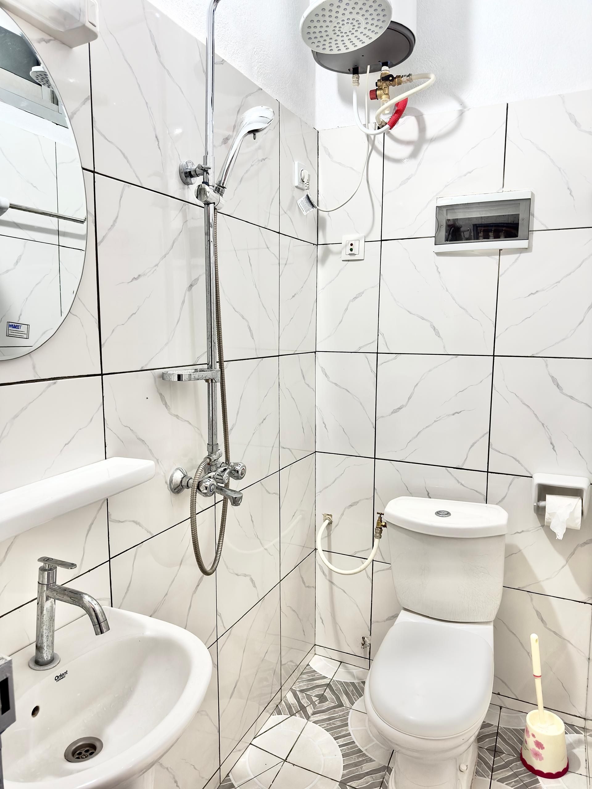 Un baño moderno con ducha, lavamanos, inodoro y espejo.
