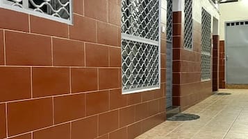 A corridor with tiled walls and floor, air conditioning units, and a door.