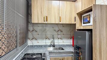 Una cocina con armarios de madera, un lavamanos de acero inoxidable, una estufa a gas y un refrigerador con pantalla digital.