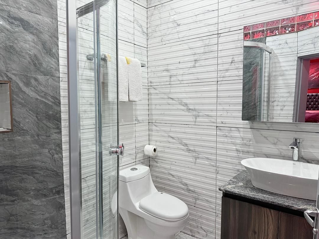 Une salle de bain moderne avec une douche à parois de verre, des toilettes blanches et un meuble-lavabo.