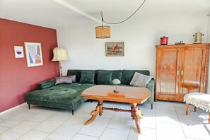 A living room with a green sofa, a wooden coffee table, a cabinet, and a hanging lamp. - Holiday apartment with 2 bedrooms (Überlingen)