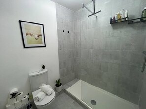 A bathroom with a toilet, a shower, a sink, and a framed picture on the wall. - Stylish 2BDR Apt with Free parking in Dublin 8 (Dublin)