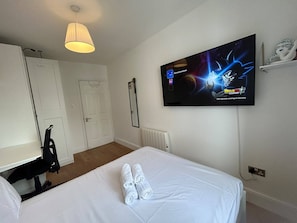 A hotel room with a bed, a TV mounted on the wall, a radiator, and a door. - Stylish 2BDR Apt with Free parking in Dublin 8 (Dublin)