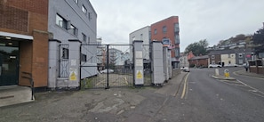A gated entrance to a building with CCTV warning signs, a pedestrian pathway, and parked cars. - Stylish 2BDR Apt with Free parking in Dublin 8 (Dublin)