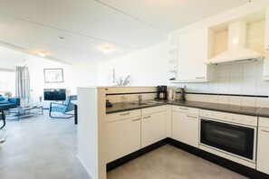 A modern kitchen with white cabinets, a black countertop, and a built-in oven. - Holiday apartment in Nes with swimming pool (Nes)