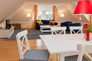 Un salon moderne avec un canapé, une table à manger et un téléviseur.