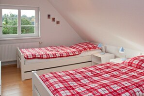 Une chambre avec deux lits, une fenêtre et un radiateur.