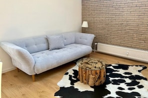 A room with a light grey sofa, a glass coffee table with a wooden base, and a black and white cowhide rug. - Apartment in Schliersee with swimming pool (Schliersee)
