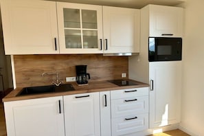 A kitchen with white cabinets, a wooden countertop, a coffee maker, and a microwave. - Apartment in Schliersee with swimming pool (Schliersee)