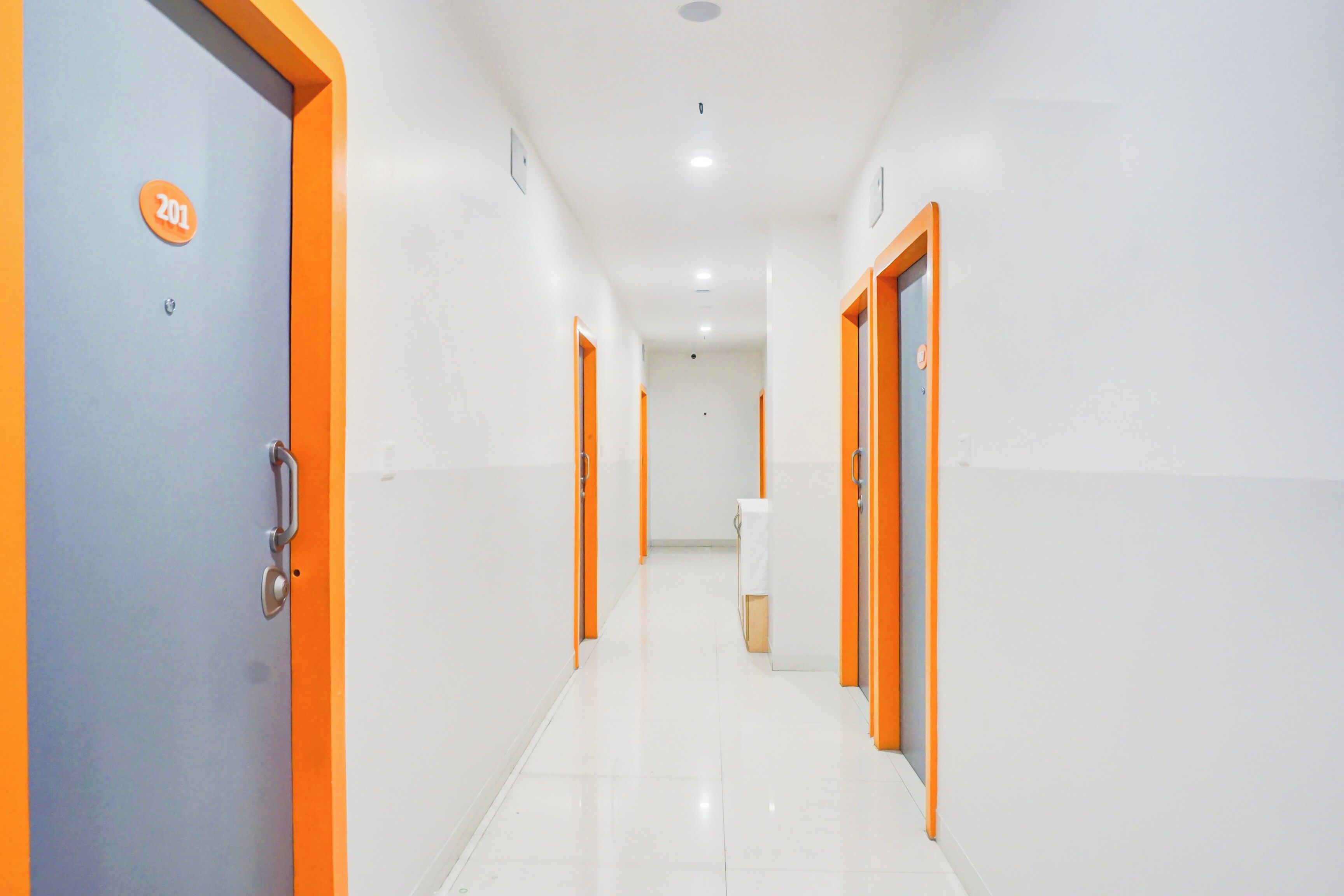 A corridor with doors, a sign, and a trash bin.