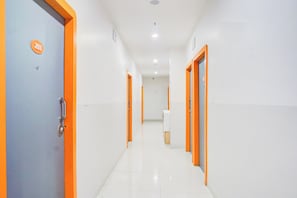 A corridor with doors, a sign, and a trash bin. - Townhouse Hadapsar (Pune)