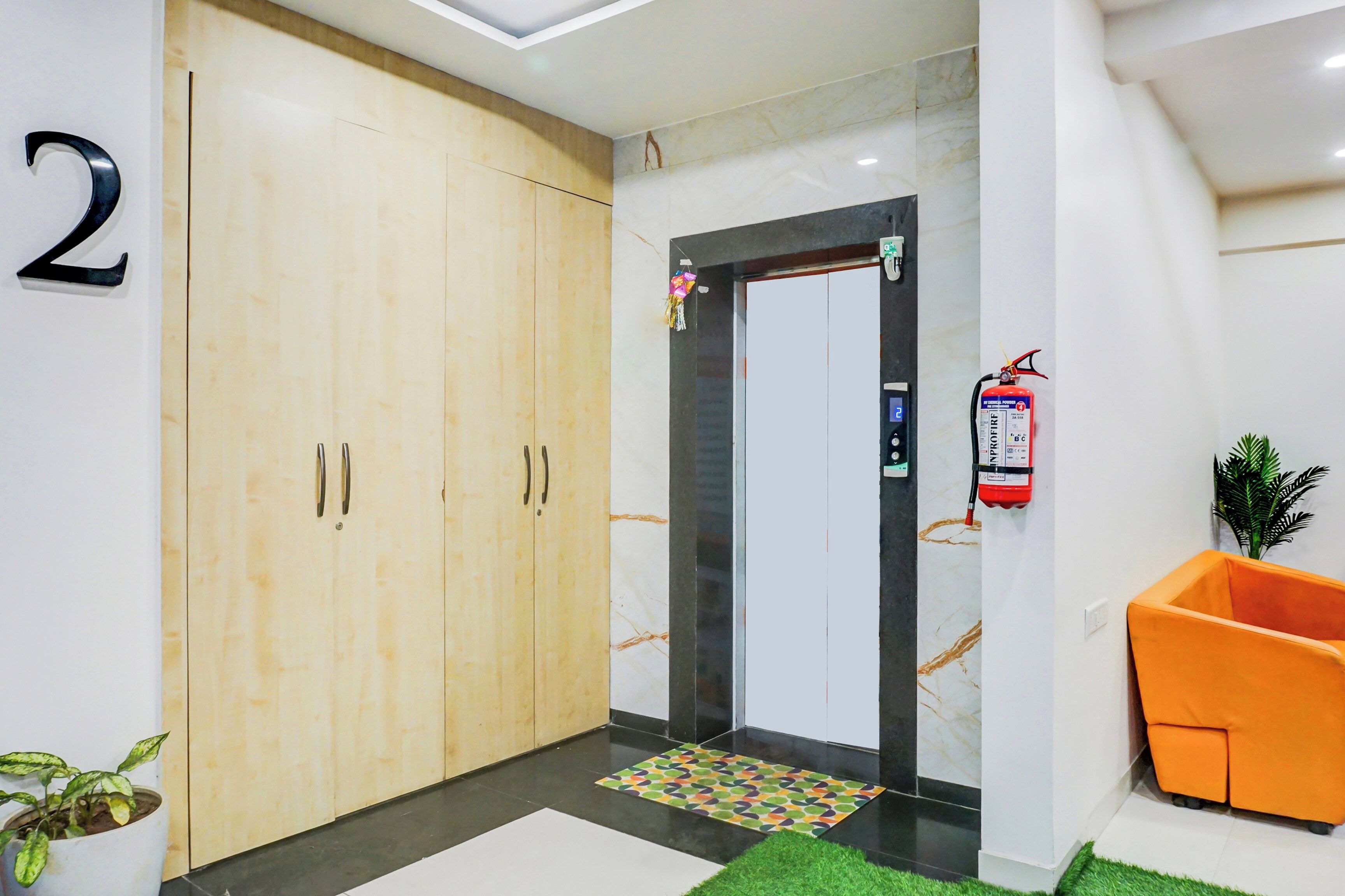 Un vestíbulo de hotel con un armario de madera, una recepción, un extintor y una planta en maceta.