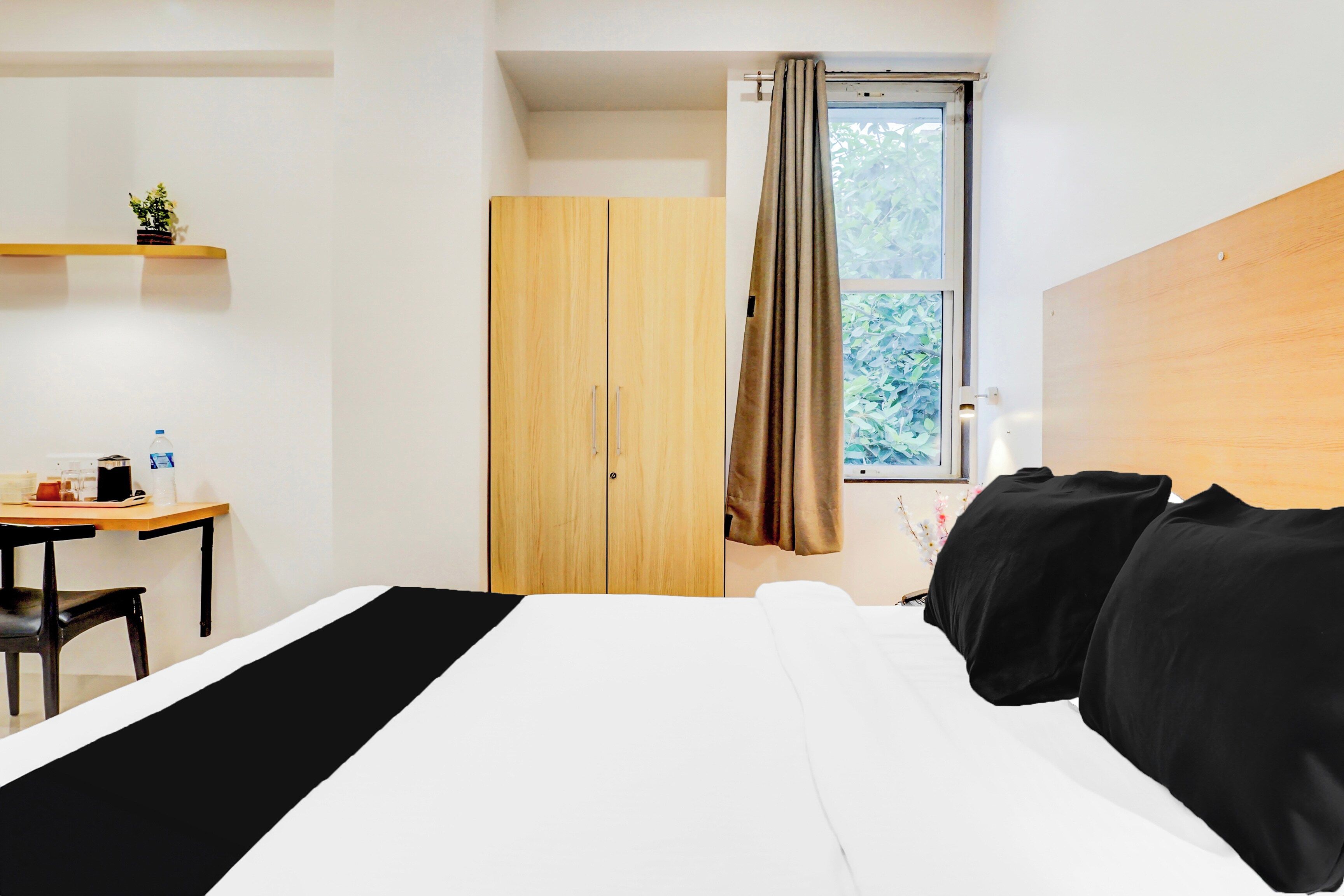 Un dormitorio con cama, escritorio, armario y ventana con cortinas.