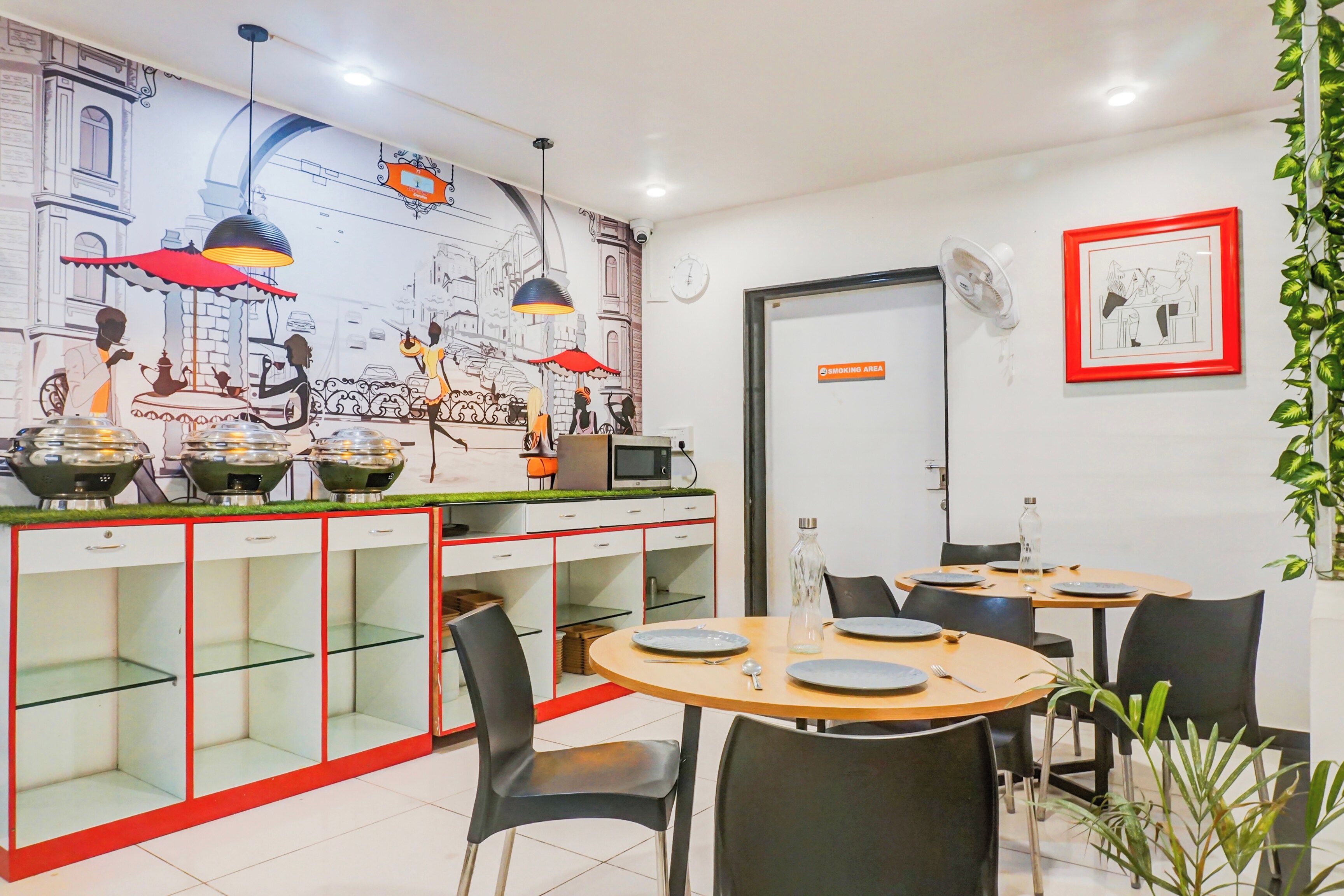 A restaurant with a mural, tables, chairs, and a clock on the wall.