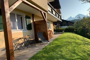 Ein Gebäude mit einem Balkon, einer Holzterrasse und einem Rasen.