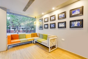 A room with a sofa, a small table, and a wall with framed pictures. - Townhouse Oak Kodambakkam (Chennai)