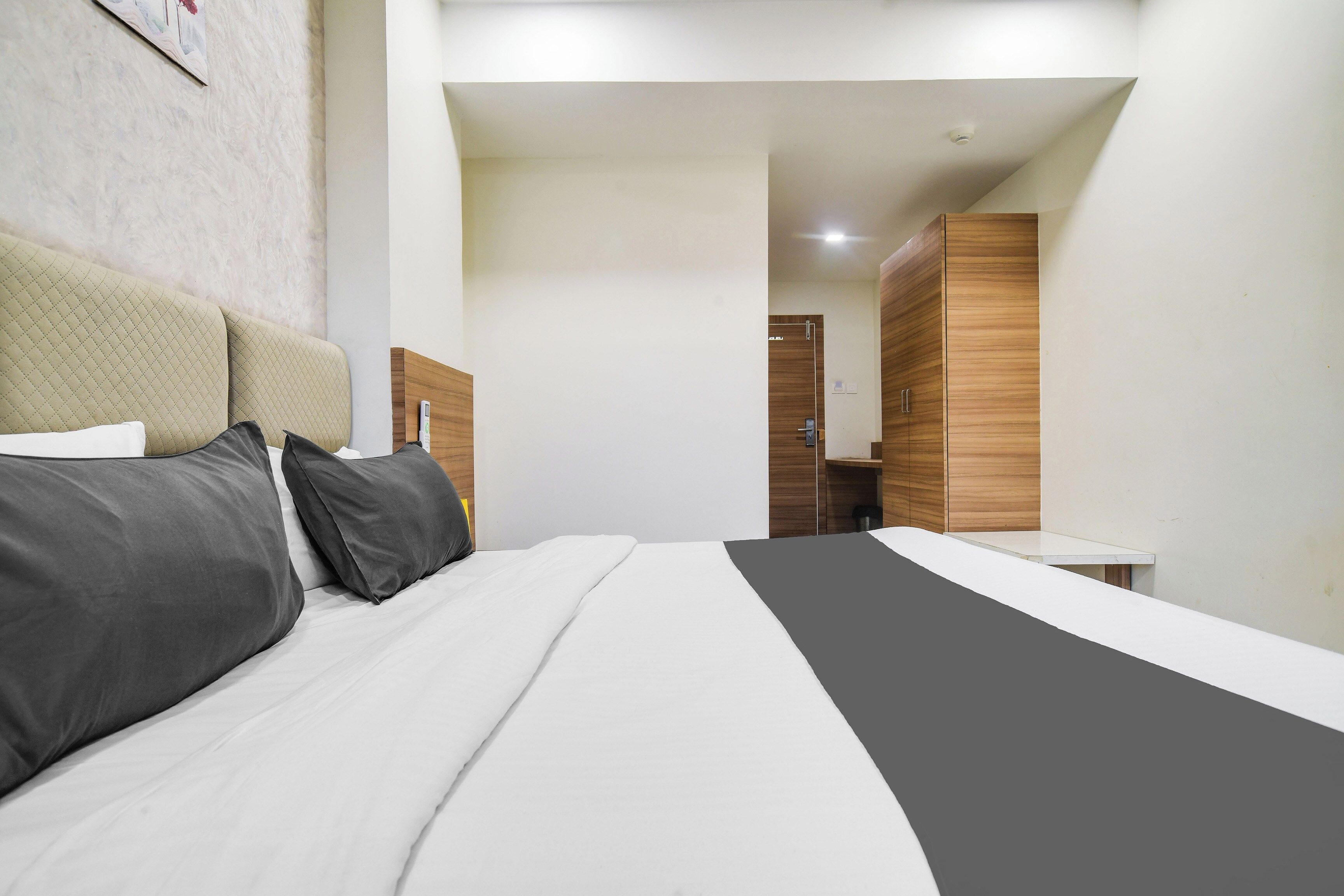 Una habitación de hotel moderna con cama, mesitas de noche, armario y baño visible a través de una puerta abierta.
