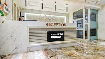 A reception desk with a sign reading 'TOWNHOUSE OAK Company Serviced' and clocks indicating different time zones.