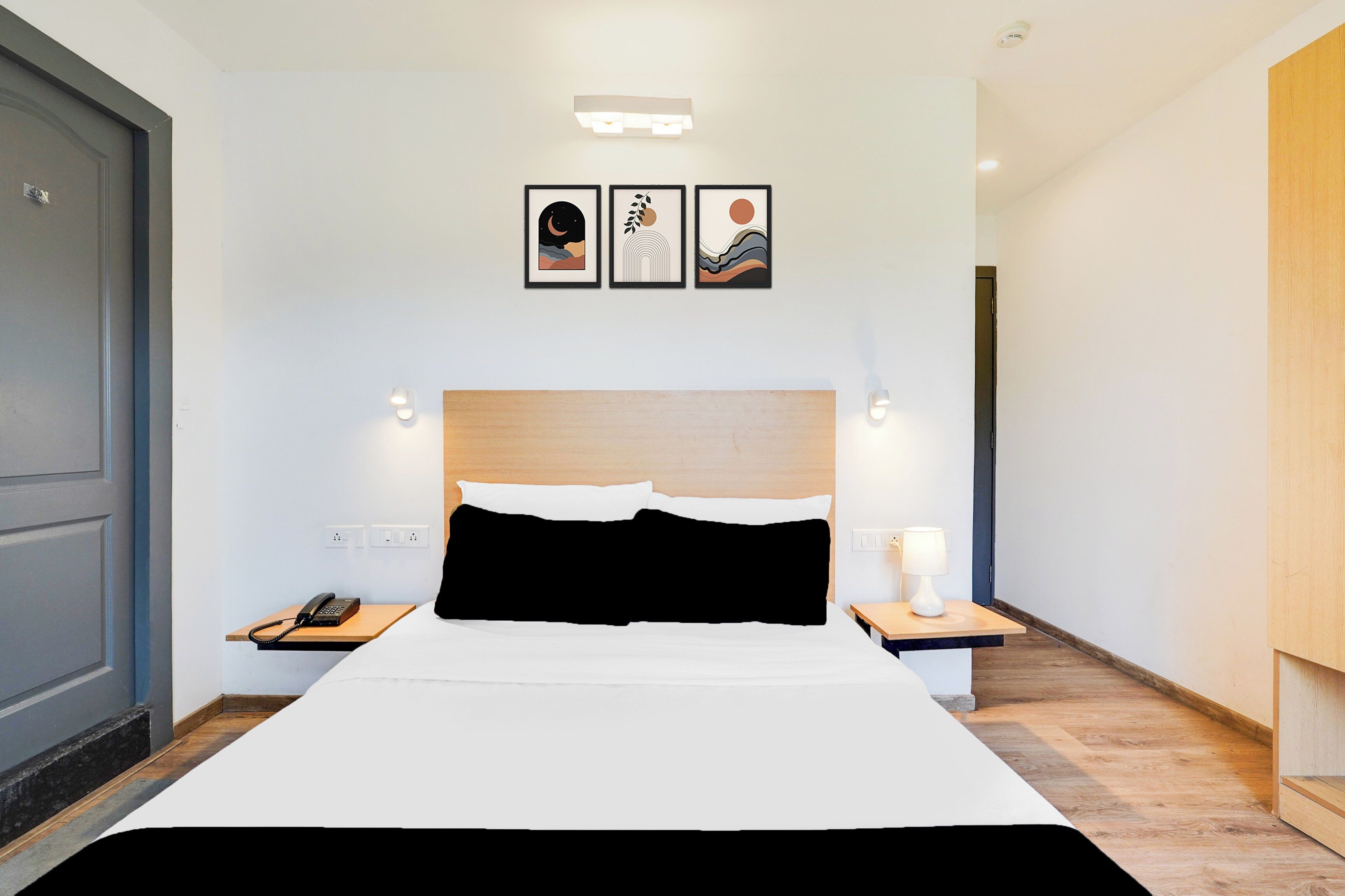 A modern hotel room with a large bed, bedside tables, a phone, and wall-mounted artwork.