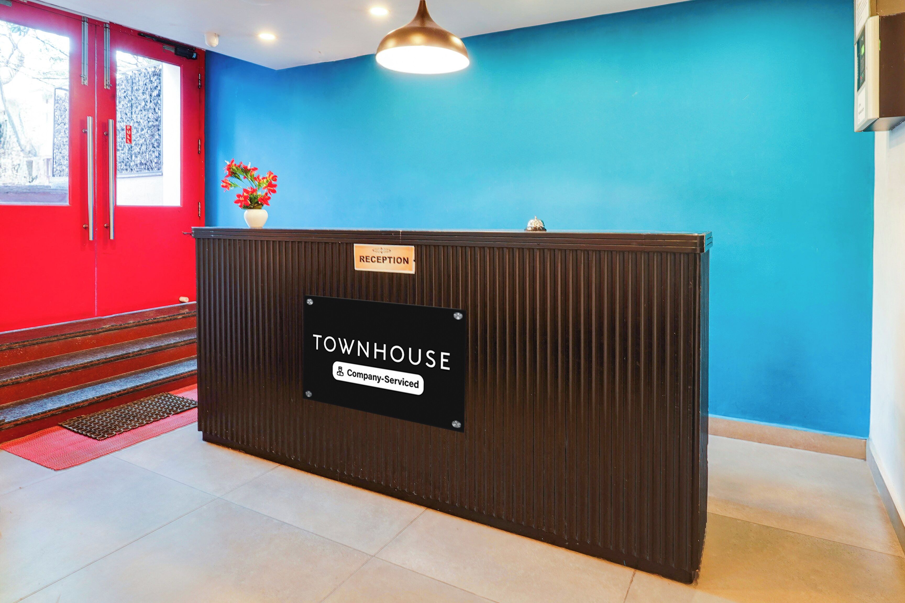 A reception desk with a 'TOWNHOUSE' sign, a 'RECEPTION' sign above it, and a 'Company-Serviced' label.