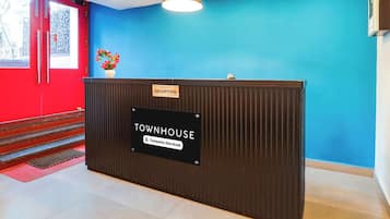 Una mesa de recepción con un letrero que dice 'TOWNHOUSE', un letrero de 'RECEPTION' encima y una etiqueta que indica 'Servicio de Empresa'.
