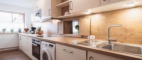 A modern kitchen with built-in appliances, a stainless steel sink, and wooden cabinetry.