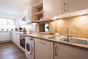 A modern kitchen with built-in appliances, a stainless steel sink, and wooden cabinetry. - Holiday apartment with 1 bedroom (Rettenberg)