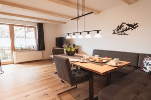 A modern dining area with a wooden table, chairs, and a sofa. - Holiday apartment with 1 bedroom (Rettenberg)