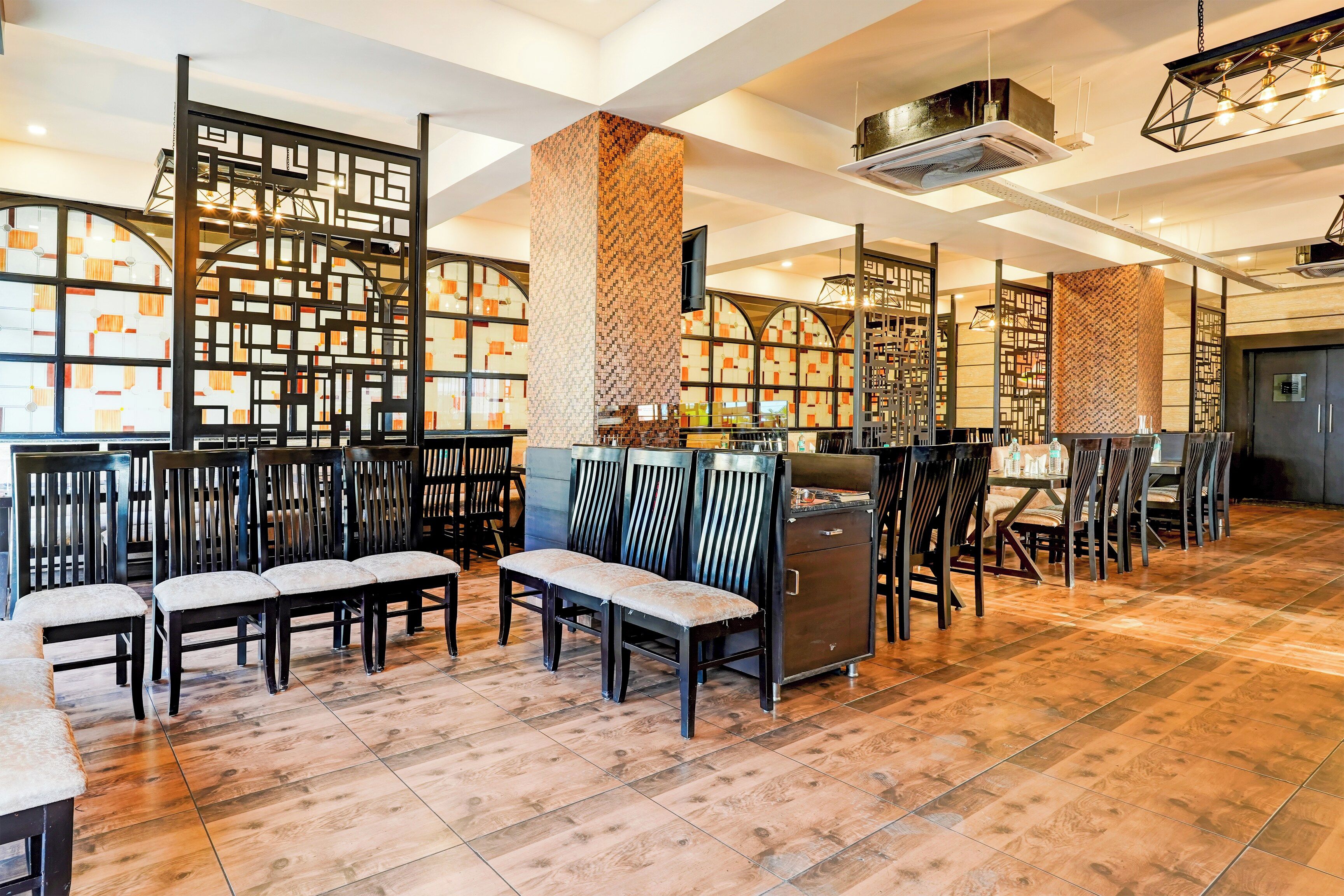 A spacious indoor area with wooden flooring, multiple seating arrangements, and decorative partitions.
