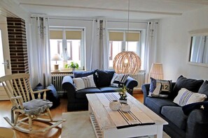 A living room with a blue sofa, a wooden rocking chair, and a white coffee table. - Föh's little house || Kappeln Stadt (Kappeln Stadt)