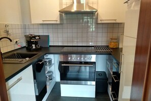 Ett kompakt kök med en inbyggd ugn, en kaffebryggare och en fläktkåpa i rostfritt stål.