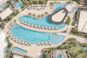 Eine Vogelperspektive zeigt einen luxuriösen Kurort mit mehreren Schwimmbecken, Liegestühlen und liebevoll gestalteten Grünflächen.