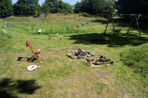 Ein Außenbereich mit Feuerstelle, Schaukel und Picknicktisch.
