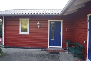 Ein rotes Gebäude mit einer blauen Tür und einer kleinen Veranda mit einer Bank.