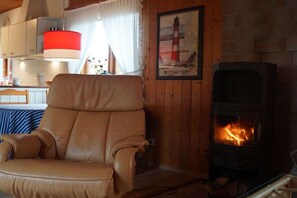 Ein Zimmer mit Ledersessel, Kamin, Holzwänden und einem gerahmten Bild.