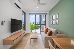 A modern living room with a flat-screen TV, a sofa, a coffee table, and a dining area. - Skypark Celeste 6, One-bedroom 6108 1Bx Ground Floor (Choeng Thale)
