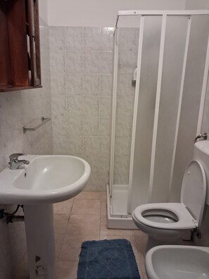 A bathroom with a sink, toilet, and shower. - Don Carlos (Buscate)