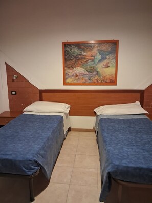A room with two beds, a wooden headboard, a painting on the wall, and a tiled floor. - Don Carlos (Buscate)