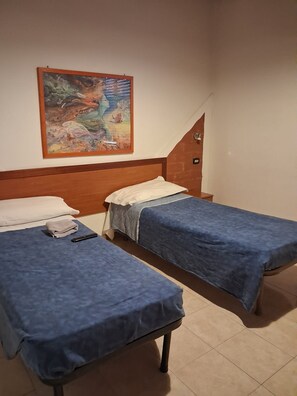 A room with two single beds, a wooden headboard, a wall-mounted painting, and a small table. - Don Carlos (Buscate)