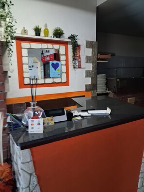 A reception area with a counter, a Coca-Cola refrigerator, a Visa card machine, and a decorative heart sign. - Don Carlos (Buscate)