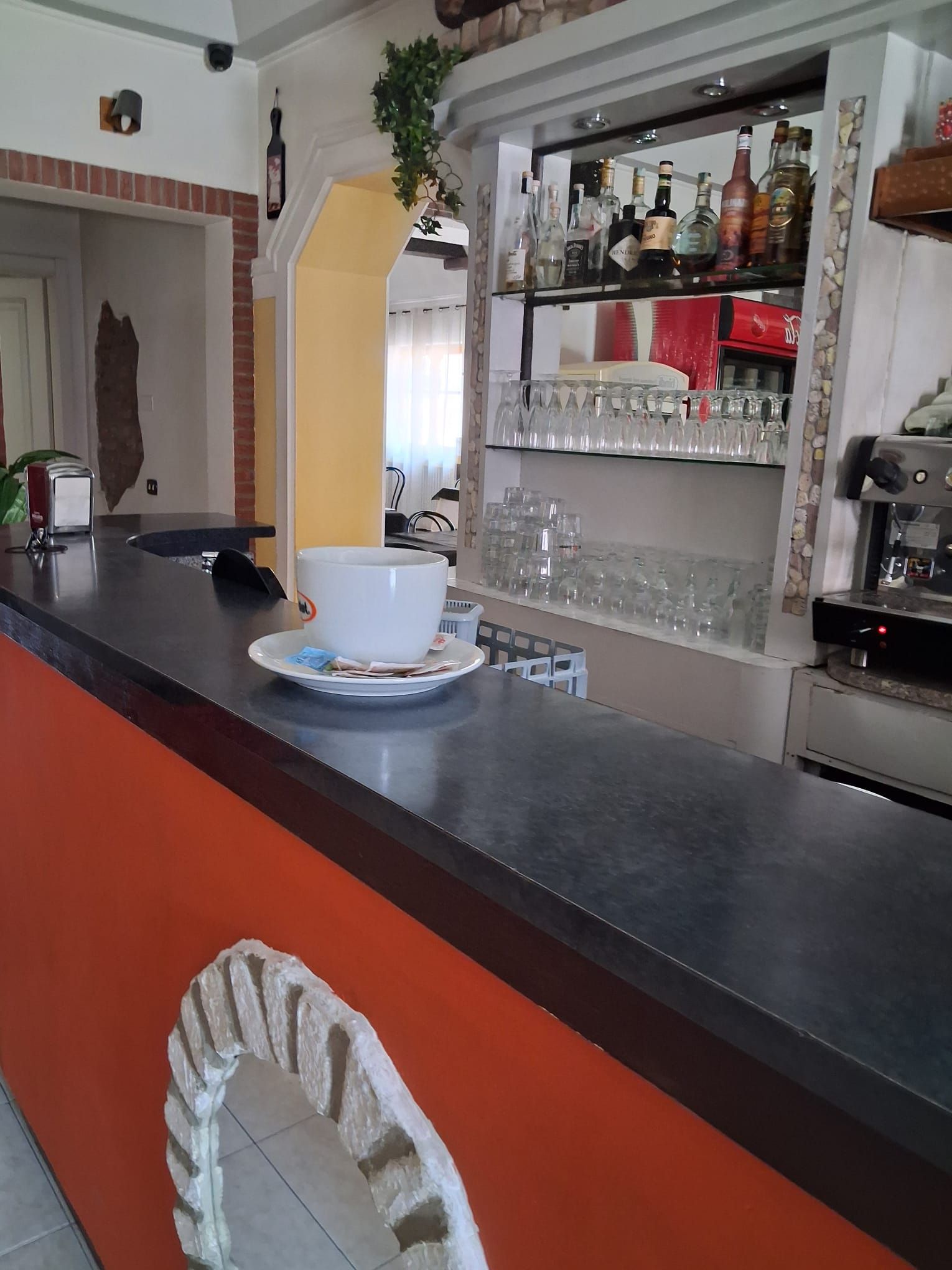 Un espace bar avec un comptoir, des étagères remplies de bouteilles et un appareil à café.