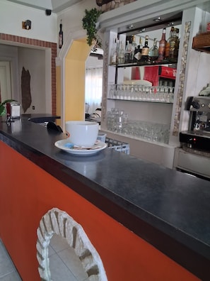 A bar area with a counter, shelves of bottles, and a coffee machine. - Don Carlos (Buscate)