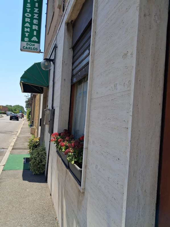 A building with a sign for 'PIZZERIA DON CARLOS' and a window with red flowers. - Don Carlos (Buscate)