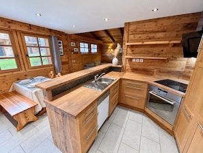 A modern kitchen with wooden cabinetry, a central island, and a built-in oven. - New Listing (Les Allues)