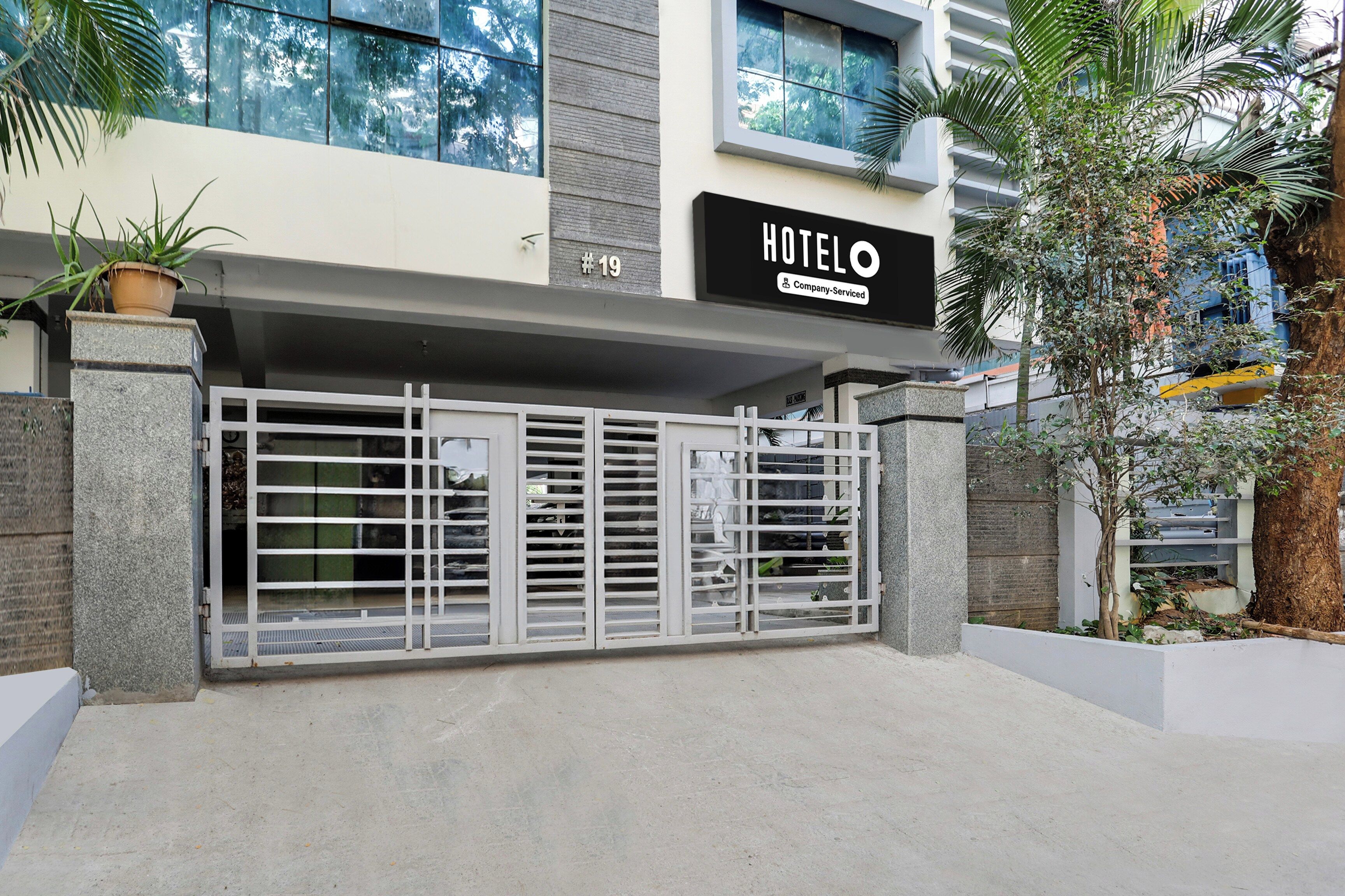 Entrada de un hotel con un camino de acceso porticado, un letrero que indica la habitación número 19 y un logotipo de la empresa.