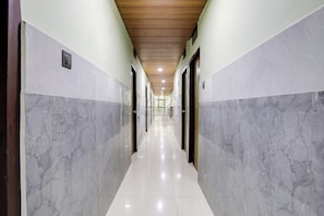 Un pasillo con paredes de mármol y techo de madera, que conduce a una habitación luminosa con ventana.
