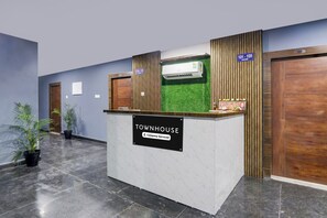 A reception desk with a sign indicating 'TOWNHOUSE Company-Serviced' in a hallway with doors numbered 101-109 and a reception area. - Townhouse Kukatpally (Hyderabad)