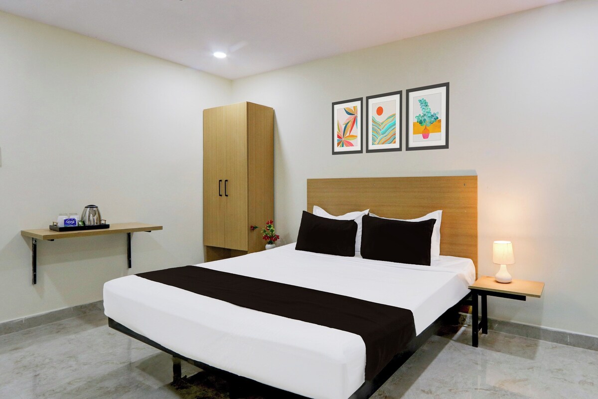 Habitación de hotel con cama, mesita de noche, pequeña mesa, armario y tres cuadros en la pared.